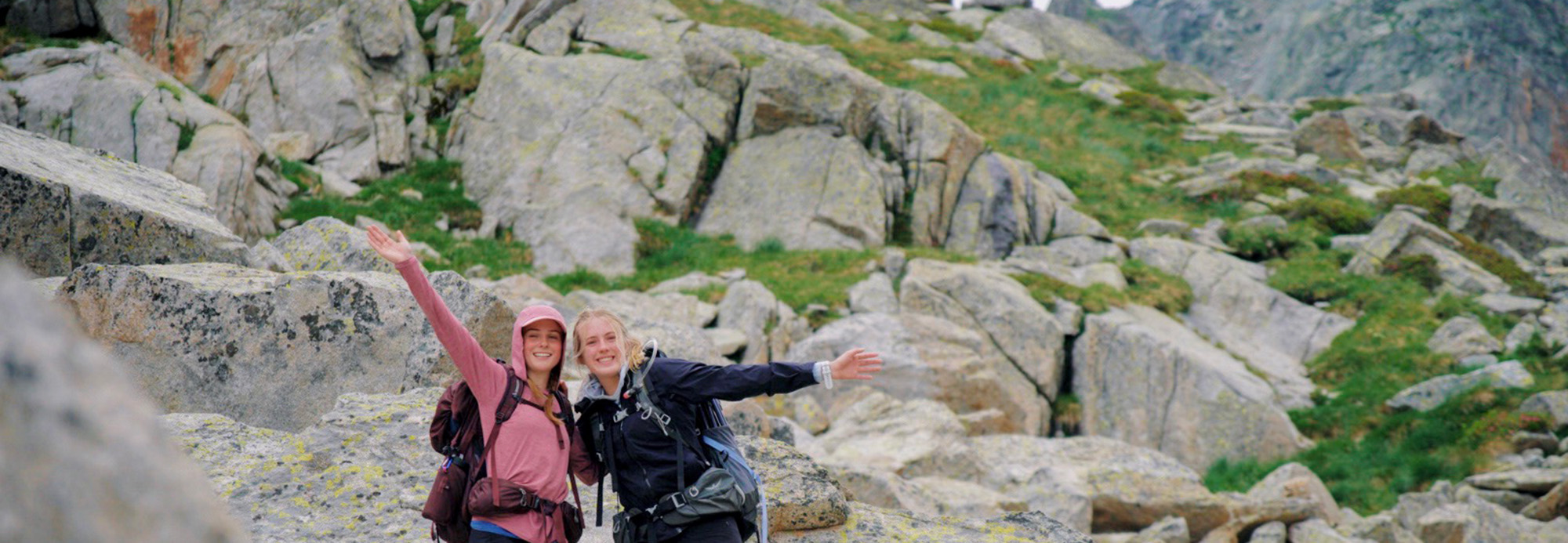 Two hikers with their hands in the air smiling.