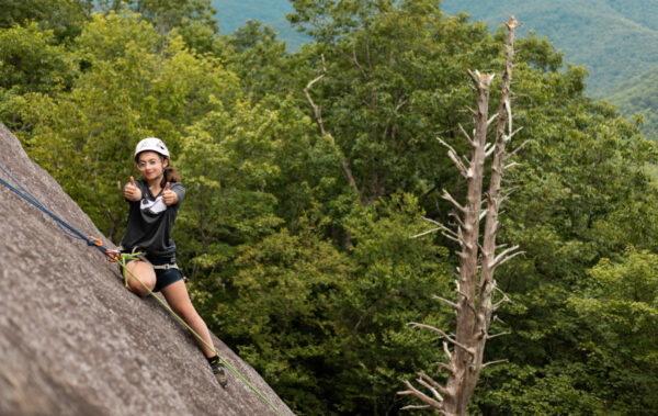 girl rock climbing giving 2 thumbs up