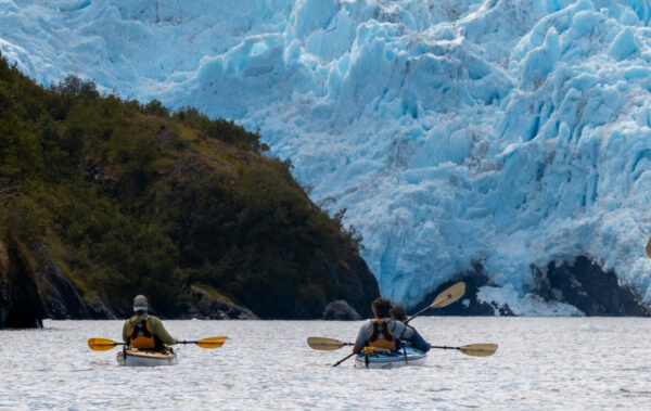 group sea kayaking towards a huge alaskan glacier