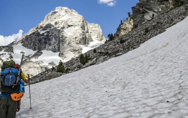 backpackers hiking through a snowfield toward Grand Teton