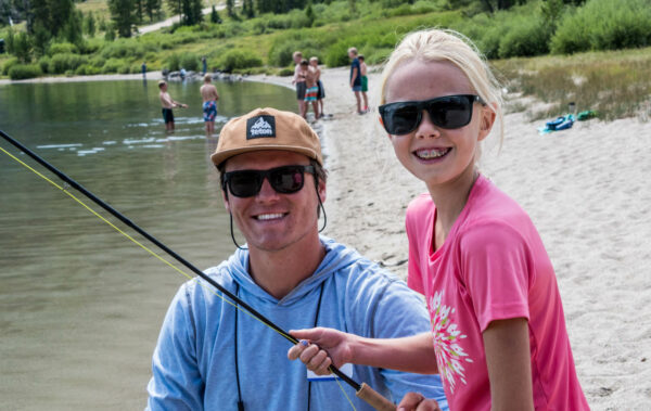 Leader teaching a traveler how to use a fishing pole