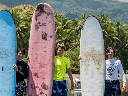 Three young surfers standing next to their boards on the shore in Costa Rica.