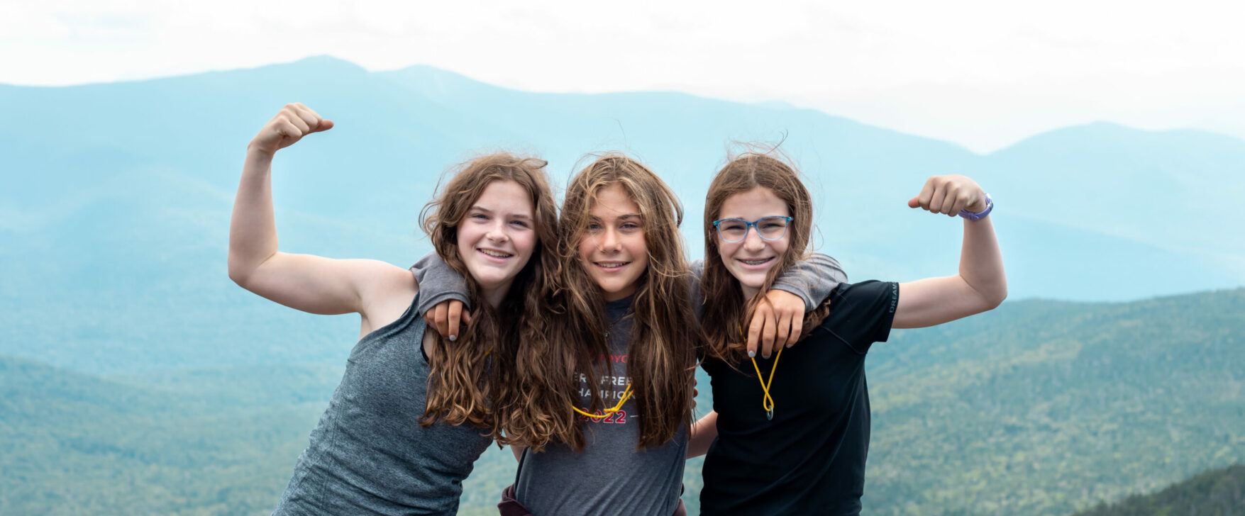 three girls posing on a mountain top