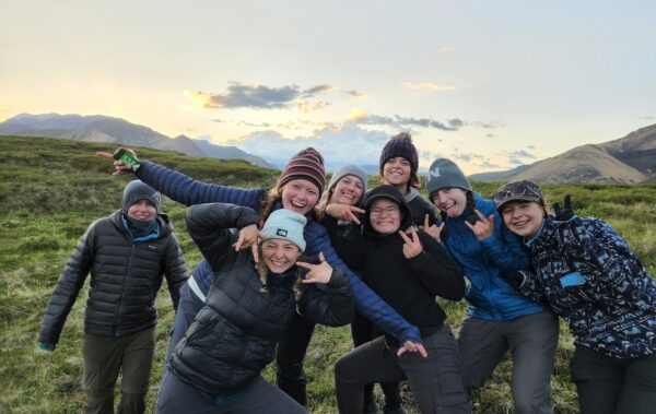 a group of students pose infront of a sunset