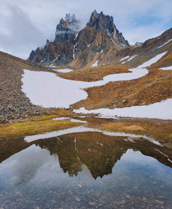 Epic view of jagged mountain peaks with a reflection of the mountains in a lake.