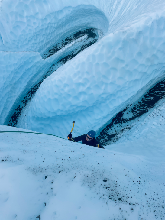 Person ice climbing up a glacial wall.