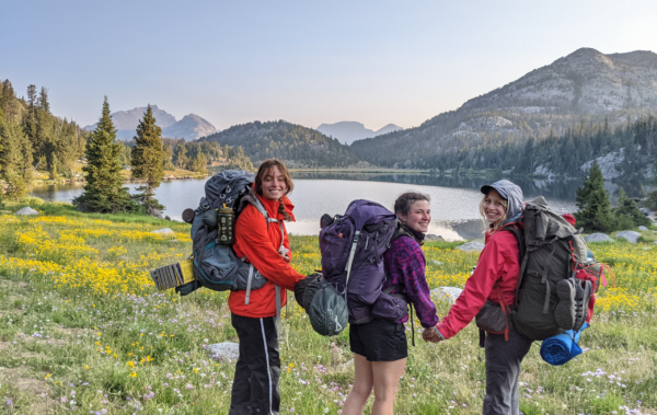 Three people with backpacking packs in the mountains.