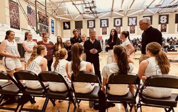 Girls basketball team at halftime with coach speaking.