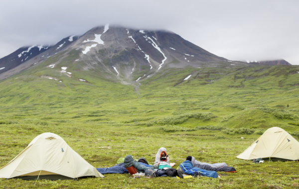 Group of campers in sleeping bags at campsite.