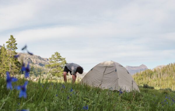 Camper setting up a tent in a field.