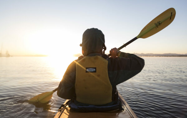 Person paddling on Yellowstone Lake in the sunrise.