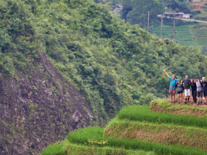Group of travelers at the edge of a trail trekking through the fields of a village in Vietnam.