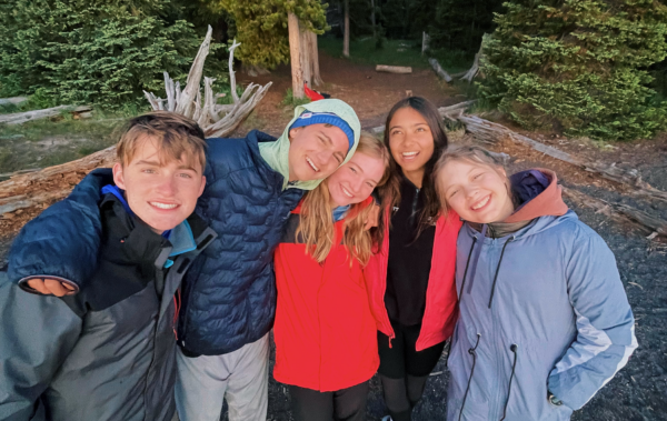 Group of students with their arms around each other smiling.