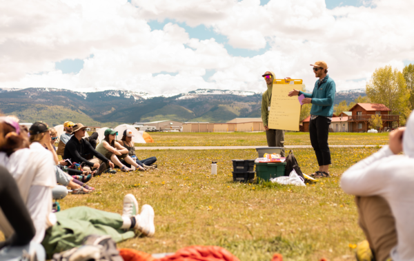 Two people presenting to a group of people in an open field