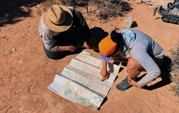 Two people looking at a map in the desert.