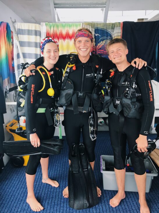 3 people with SCUBA gear on a a boat.