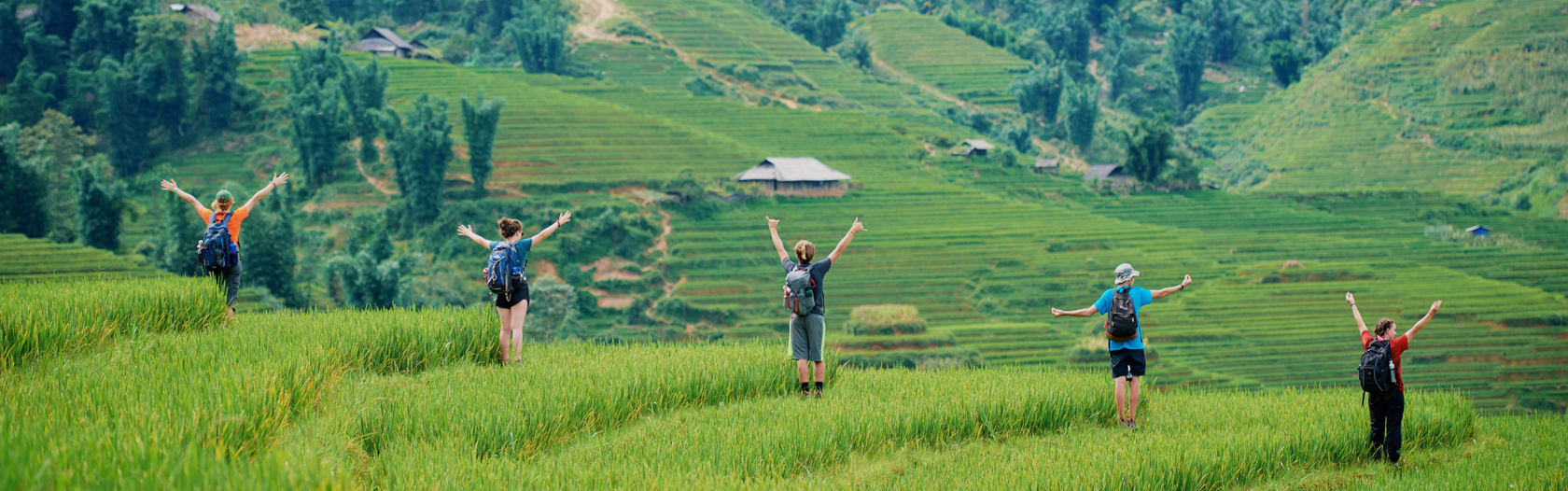 Five people with their arms in the air in rice fields in Vietnam.