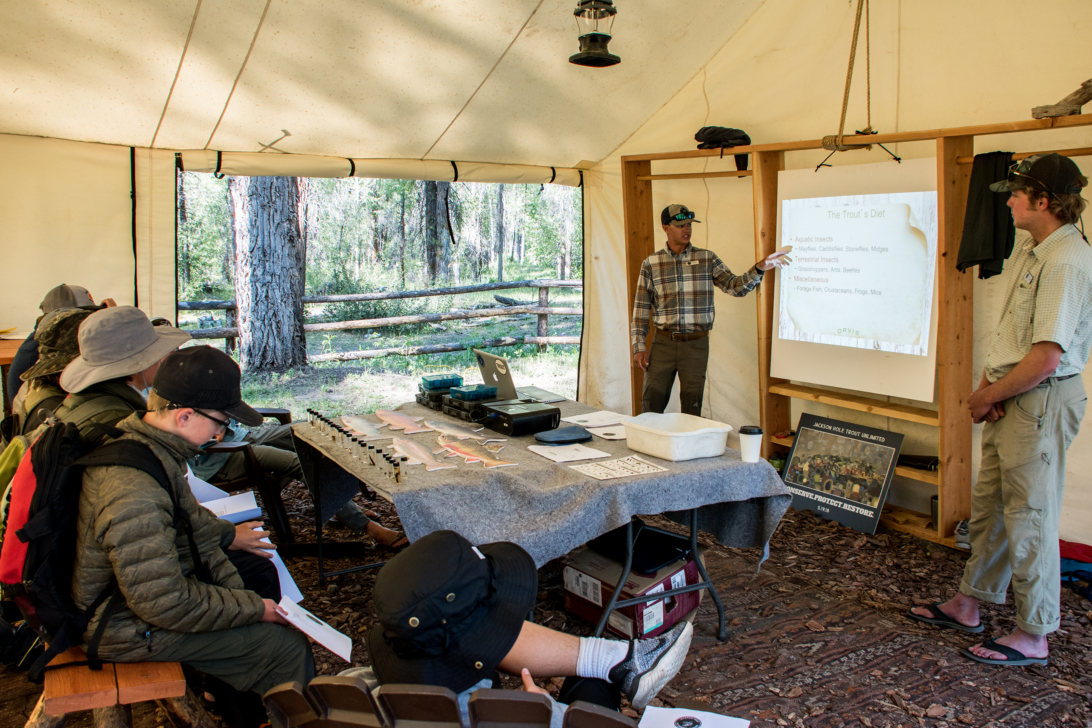 Campers at a fly fishing seminar viewing a presentation.