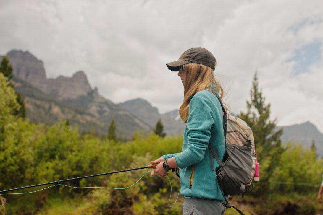 Profile of a young girl with a fishing rod in the mountains.