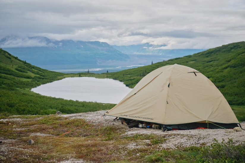 A tent set up above a lake on a flat surface.