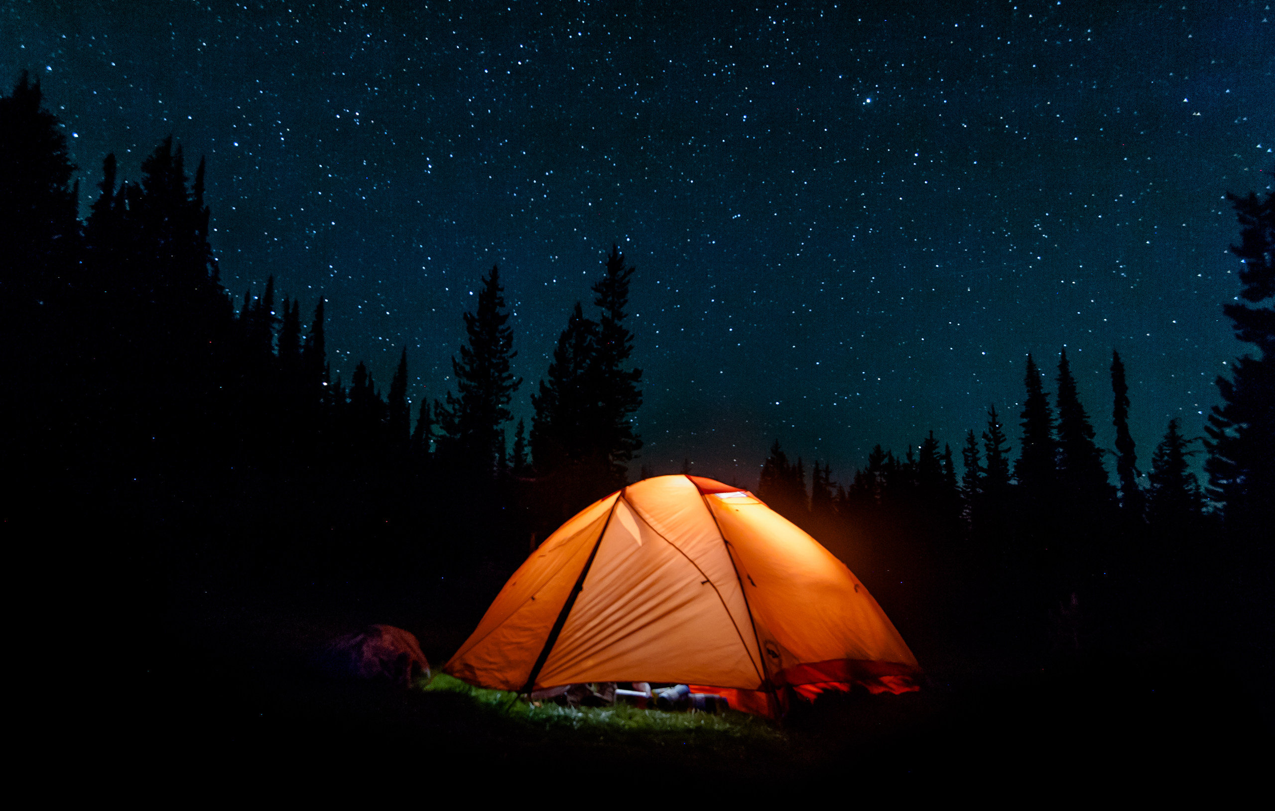 Orange tent lit up with lights under a starry sky.