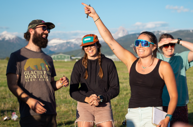 People smiling and instructing in a field.